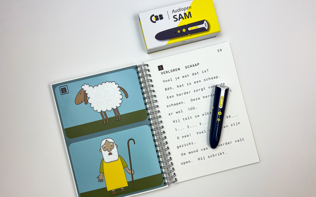 'My little toddler bible' lies open on a table. The story 'lost sheep' is on the right page in large print and in braille. At the top of the left page is a tactile image of a sheep, below that is a tactile image of a shepherd with a staff. Above the book is a box containing Audiopen Sam.